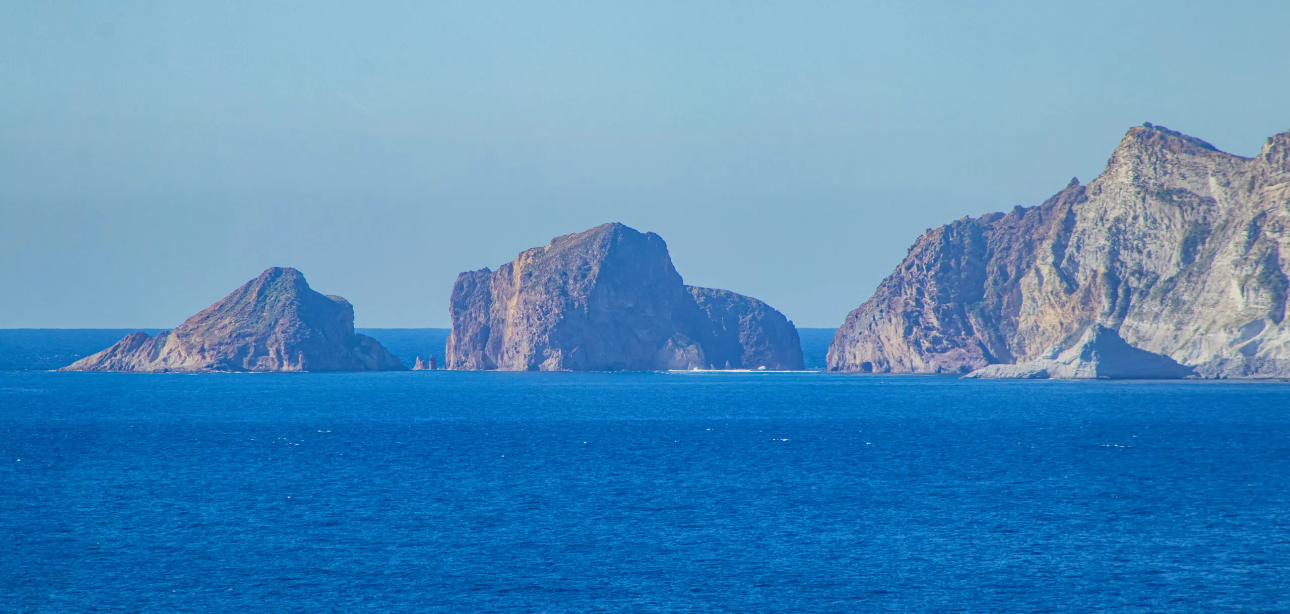 Vista panoramica dell’isola di Palmarola, parte dell’Arcipelago Ponziano, con le sue imponenti formazioni rocciose che emergono dalle acque cristalline del Mar Tirreno.
