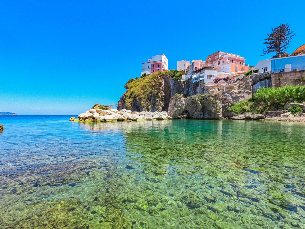 Veduta delle acque cristalline di Ponza con case colorate a picco sul mare