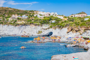 Vista sulla cala Piscine Naturali a Ponza, nella zona di Le Forna, con scogliere bianche, mare cristallino ed ombrelloni colorati. Un angolo di paradiso perfetto per rilassarsi e nuotare.