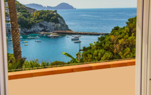 Vista mozzafiato sulle Piscine Naturali di Ponza da una terrazza privata, con barche ormeggiate e un mare cristallino.